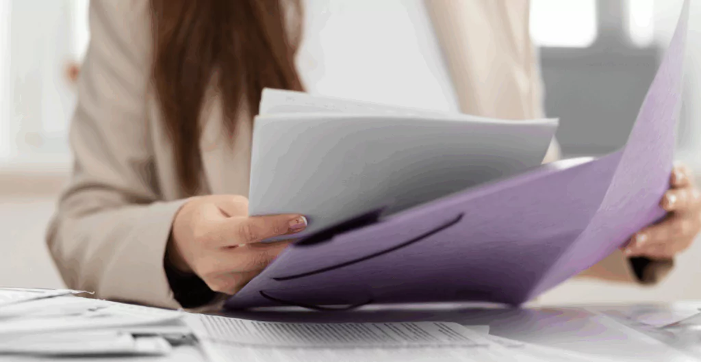 Mulher segurando papéis em uma pasta lilás